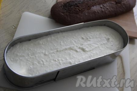 Приступаем к сборке торта "Баунти", для этого полностью остывший бисквит нужно разрезать на две части (на 2 коржа). По желанию, можно пропитать коржи кокосовым сиропом. Нижнюю часть бисквита выложить на дно формы и сверху выложить весь крем, разровнять.