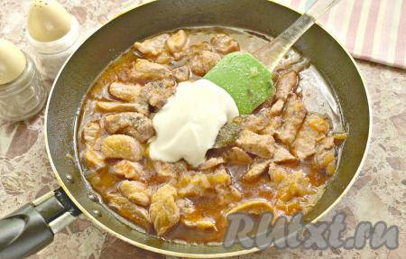 Поджарку из свинины с подливкой солим по вкусу и приправляем молотым перцем. Можете добавить своих любимых специй. Выкладываем сметану, перемешиваем. Продолжаем тушить на сковороде ещё пару минут.