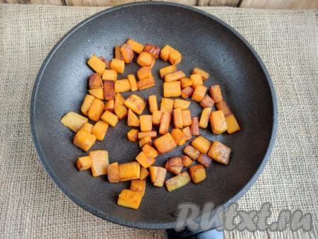 Разогреть в сковороде 1,5 столовые ложки растительного масла, выложить нарезанную тыкву. Лучше всего взять достаточно большую сковороду (например, диаметром 22-24 см), чтобы выложить кусочки тыквы в один слой. Обжарить тыкву на среднем огне до румяной корочки со всех сторон, периодически перемешивая.