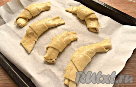 Заготовки круассанов с вареньем выкладываем на противень, который лучше застелить бумагой для выпечки. Сверху круассаны смазываем взбитым яйцом для придания красивого цвета готовой выпечке.