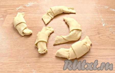 Начиная с широкого края с вареньем, треугольники сворачиваем в форме рогаликов. Заготовкам придаём форму полумесяца.