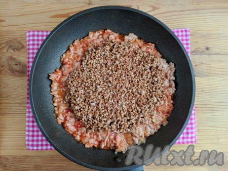 К фаршу, тушёному с томатной пастой, всыпать промытую гречку, посолить, добавить специи, поперчить.