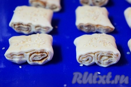 Духовку разогреваем до 200 градусов. Подготовленные слойки с сахаром и корицей выкладываем на силиконовый коврик (или на пергамент), смазываем верх слоечек оставшимся взбитым яйцом и, по желанию, посыпаем кунжутом. Выпекаем слойки в течение 20 минут (до золотистой корочки).