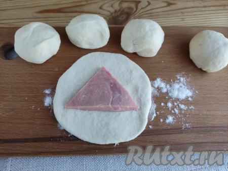 Разделить тесто на 5 равных частей. Каждую часть скатать в шарик. Шарик на припылённой мукой поверхности раскатать в лепёшку диаметром около 6-7 см. По центру лепешки выложить треугольник из колбасы. 