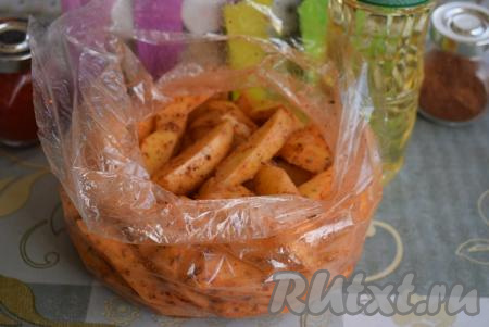 Перекручиваем верх рукава для запекания с картофелем рукой и трясём для того, чтобы каждая долька покрылась маслом, солью и специями.