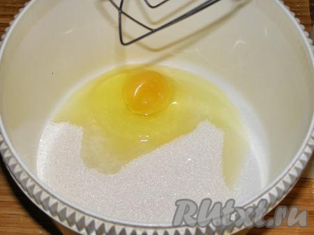 В достаточно объёмную миску (или в чашу для взбивания) насыпаем сахар, добавляем яйцо, с помощью венчика (или миксером) смешиваем практически до однородного состояния.