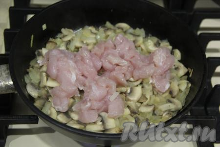 Куриное филе нарезать на кубики и добавить в сковороду к луку и грибам, перемешать.