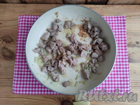 2 столовые ложки растительного масла влить в сковороду, разогреть, затем выложить свинину с луком и обжарить на среднем огне, помешивая, в течение 4-5 минут, посолить, сдобрить специями, убрать с огня и дать немного остыть.