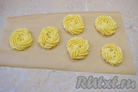 Получившееся песочное тесто можно просто скатать в шарики и выкладывать их на небольшом расстоянии друг от друга на противень, застеленный пергаментом, слегка придавливая шарики рукой. Я же решила выложить тесто в кондитерский мешок и отсаживать его на застеленный противень, оставляя небольшое расстояние между заготовками печенья. Из указанного количества ингредиентов обычно получается 13-15 печенюшек.