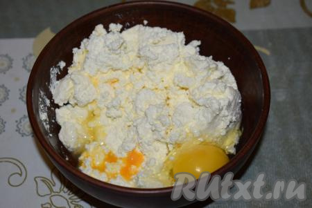 В миску выкладываем творог и разбиваем яйца.