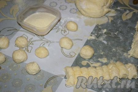 Далее отделяем часть теста, скатываем в трубочку и нарезаем её на кусочки. Затем кусочки теста скатываем в шарики размером с грецкий орех. Манную крупу насыпаем в глубокую мисочку.