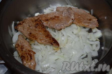 Обжаренные отбивные складываем в кастрюлю на луковую подушку.