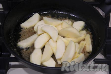 На среднем огне, помешивая, растворить сахар. Как только сахар начнёт приобретать карамельный оттенок, выложить дольки яблок.