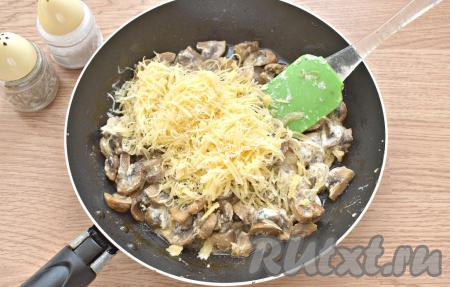 Убираем сковороду с шампиньонами с плиты. По вкусу солим и перчим. Добавляем натёртый на средней тёрке сыр.