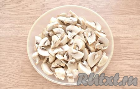 Удаляем со свежих шампиньонов загрязнения, промываем их, а затем выкладываем на тканевое полотенце, даём грибочкам немного обсохнуть. Шампиньоны нарезаем на средние ломтики. Сильно мельчить не нужно. Луковицу очищаем и нарезаем её на тонкие полукольца.