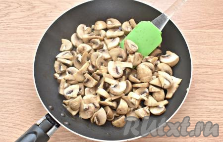 Прогреваем поверхность сковороды, масло пока добавлять не нужно. Перекладываем на горячую сковороду нарезанные грибы. Нагрев плиты делаем максимальным. Периодически перемешивая, начинаем обжаривать шампиньоны на сухой сковороде. Спустя 3-4 минуты из грибов выделится сок. Продолжаем обжаривать шампиньоны до тех пор, пока этот сок полностью не выпарится (на это потребуется минуты 2-3).