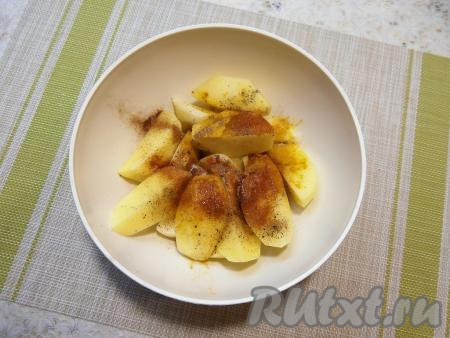 Картофельные дольки посыпать солью, куркумой, чёрным молотым перцем, паприкой и мускатным орехом, влить растительное масло.