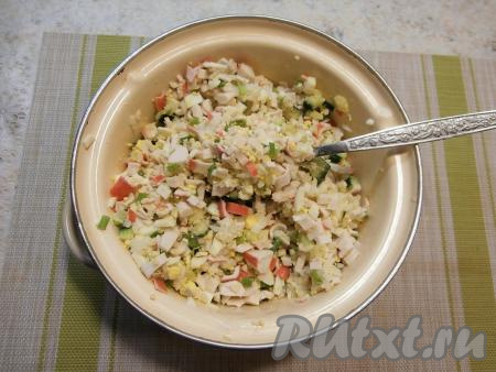В кастрюле (или в глубокой миске) соединить крабовые палочки, зелёный лук, яйца, рис, огурец. Сюда же выложить кукурузу без жидкости. Тщательно перемешать получившийся салат, посолить его.