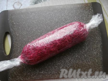 Начиная со&nbsp;стороны с селёдкой и помогая себе пищевой плёнкой, свернуть аккуратно всё в рулет. Края плёнки закрутить, как конфету. Отправить рулет в холодильник на 2-3 часа.