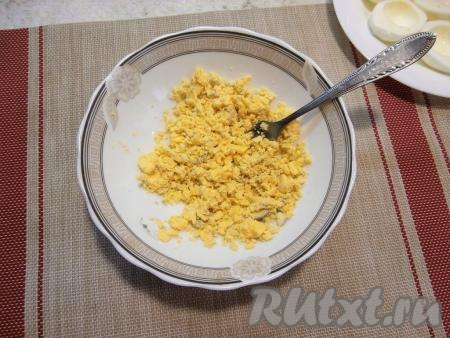 Желтки переложить в тарелку, хорошо размять их вилкой.