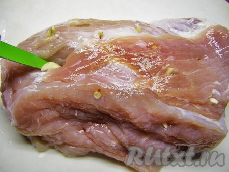 По прошествии времени достаём кусочек свинины из рассола и слегка просушиваем бумажным полотенцем. Ножом делаем в мясе проколы в произвольном порядке и вставляем в них нарезанный чеснок.