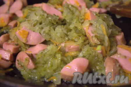 К обжаренным овощам и сосискам добавить натёртые солёные огурцы и обжаривать 2-3 минуты, периодически помешивая.