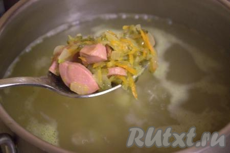 После того как картофель с перловкой станут мягкими (будут полностью готовы), переложить в кастрюлю обжаренные овощи с сосисками.