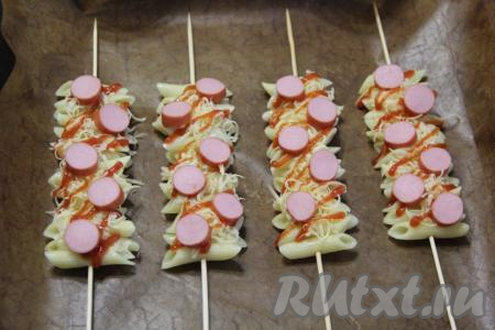 Сосиски нарезать на кружочки и выложить поверх макарон с сыром.&nbsp;