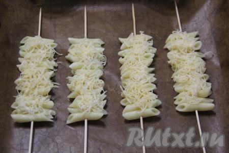 Сыр натереть на крупной тёрке. Частью натёртого сыра присыпать макароны.&nbsp;