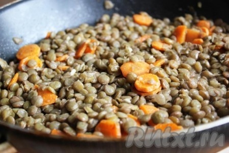 Добавьте к моркови сваренную чечевицу, мелко порубленный или пропущенный через пресс чеснок, перемешайте, уменьшите огонь до минимума и немного потомите всё вместе.