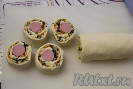 Завернуть сосиски в тесто плотным рулетом, а затем разрезать на кусочки шириной, примерно, 2 см.