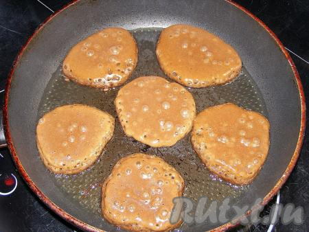 В сковородке на сильном огне разогреваем подсолнечное масло, затем уменьшаем огонь до среднего. В горячее масло выкладываем по столовой ложке шоколадного теста в виде оладий. Жарим оладушки, примерно, 1,5-2 минуты. По истечении этого времени на поверхности оладий будут появляться и лопаться пузырьки, а снизу появится поджаристая корочка.