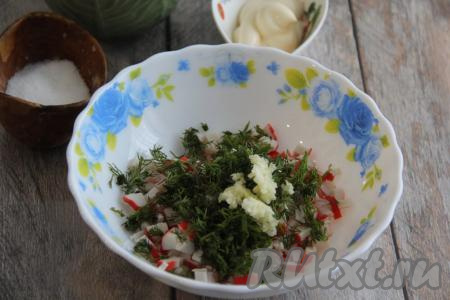 В миску с крабовыми палочками и укропом выложить очищенный и пропущенный через пресс чеснок.