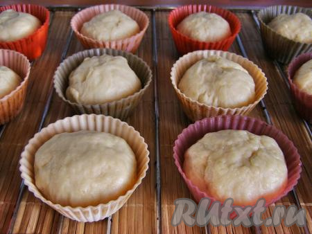 Обминаем тесто и делим его на одинаковые кусочки. У меня получилось 12 кусочков. Кусочки теста скатываем в шарики. Формочки для выпечки слегка смазываем растительным маслом и выкладываем в них шарики из теста. Для выпечки ромовой бабы лучше всего взять жестяные или силиконовые формочки с волнистыми бортиками. Оставляем тесто в формочках минут на 20 для расстойки.