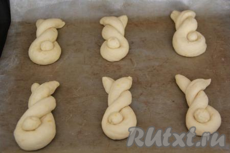 Противень застелить тефлоновым ковриком (или пергаментной бумагой), выложить получившуюся булочку-спираль, в изгиб вложить шарик теста и слегка прижать. Аналогично сформировать и выложить на противень все заготовки пасхальных булочек, оставить их для расстойки минут на 30.