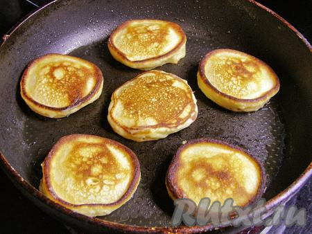 Переворачиваем оладьи лопаточкой и жарим ещё около двух минут с другой стороны, затем перекладываем на тарелку. Перед тем как налить очередную порцию теста, добавляем в сковородку немного масла и разогреваем его. Постепенно готовим все оладушки.