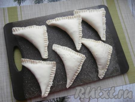 Сложить слойки треугольниками, соединяя противоположные углы и хорошенько придавливая края (можно для этого воспользоваться вилкой). Переложить слоечки на застеленный пергаментной бумагой противень.