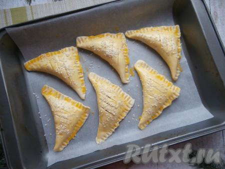 Желток расколотить вилкой и смазать им слойки, сверху посыпать кунжутом. Острым ножом на каждой заготовке сделать сверху по 2-3 надреза.