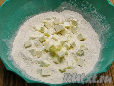 В получившуюся смесь выкладываем холодное сливочное масло, нарезанное на кубики.