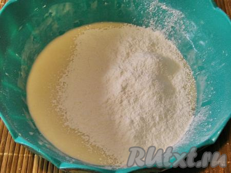 В получившуюся смесь всыпаем часть просеянной муки и перемешиваем. Далее, также понемногу, добавляем ещё муку и замешиваем тесто сначала ложкой, а когда оно станет достаточно плотным и ложкой будет трудно перемешивать, вымешиваем его руками.