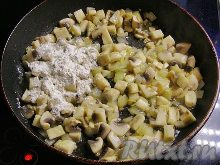 Добавляем в сковородку с луком и чесноком подготовленные грибы, перемешиваем и обжариваем 6-7 минут, помешивая. Всыпаем в сковороду муку, ещё раз хорошо перемешиваем и обжариваем, помешивая, около 2 минут.