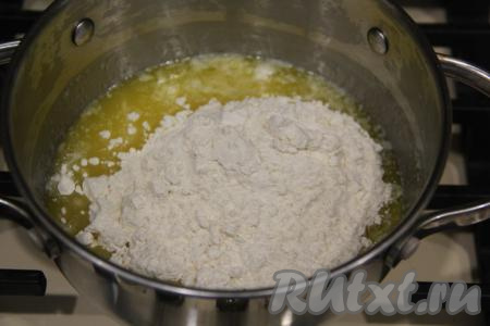 Приготовить соус бешамель, для этого в небольшую кастрюлю (или в сотейник) выложить сливочное масло и растопить его на среднем огне. Не снимая кастрюлю с огня, добавить муку в масляную массу.