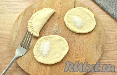 На каждую заготовку кладём немного (по вкусу) сахара. Складываем круглые заготовки пополам, формируя подобие чебурека, скрепляя края и прижимая их вилкой, как на фото. Таким же способом формируем пышки из оставшегося теста. У меня получилось 15 штук.