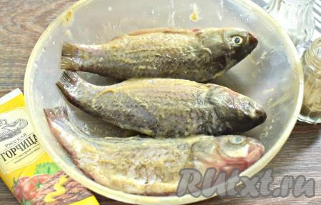 Карасей внутри и снаружи натираем по вкусу солью и молотым чёрным перцем. Хорошо обмазываем горчицей (или майонезом, или сметаной). Оставляем карасей мариноваться минут на 20.