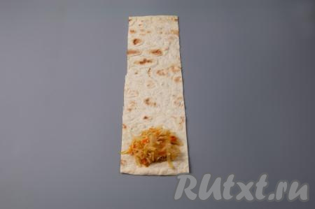 Выложите, примерно, одну столовую ложку с горкой начинки из капусты на край полоски из лаваша.
