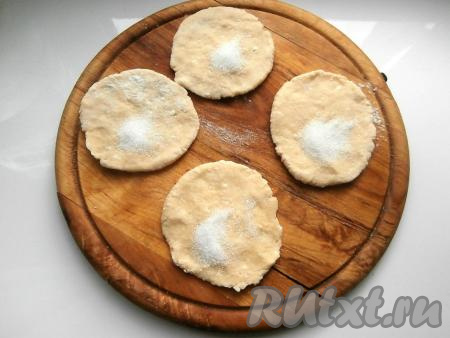 Разделить тесто на небольшие кусочки (я обычно делю на 12-15 кусочков), раскатать в лепёшки толщиной 0,5 сантиметра. В середину каждой лепёшки насыпать по 0,5 чайной ложки сахара.