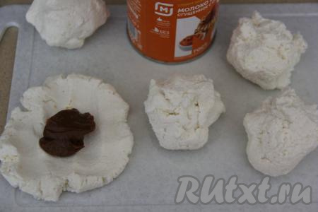 Из каждой части творожной массы сформировать лепёшку и выложить в центр по 1 чайной ложке варёной сгущёнки.