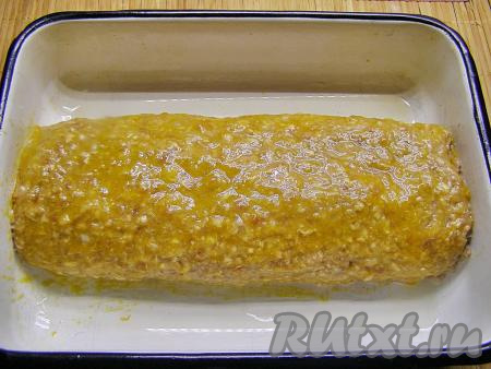 Не снимая плёнку, переносим рулет в смазанную маслом форму для запекания (или на противень), затем аккуратно достаём плёнку из-под рулета. Смазываем верх и бока рулета взбитым желтком.