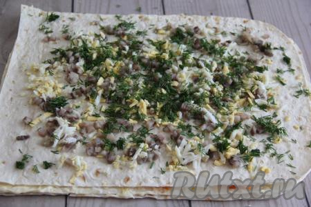 Накрыть третьим листом лаваша, тоже слегка прижать его. Филе селёдки и зелень мелко нарезать. Яйцо почистить и натереть на тёрке. Выложить равномерно селёдку, яйцо и зелень на третий лист лаваша.