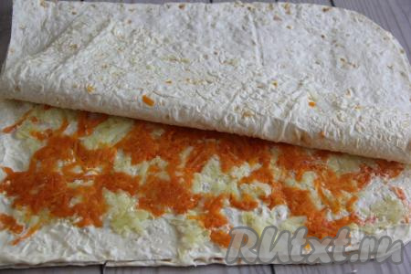 Выложить сверху второй лист лаваша, слегка прижать его рукой. Второй лист лаваша тоже смазать майонезом, также слегка отступив от краёв лаваша, затем равномерно разложить очищенные и натёртые на тёрке картошку и морковь. Слегка посолить.